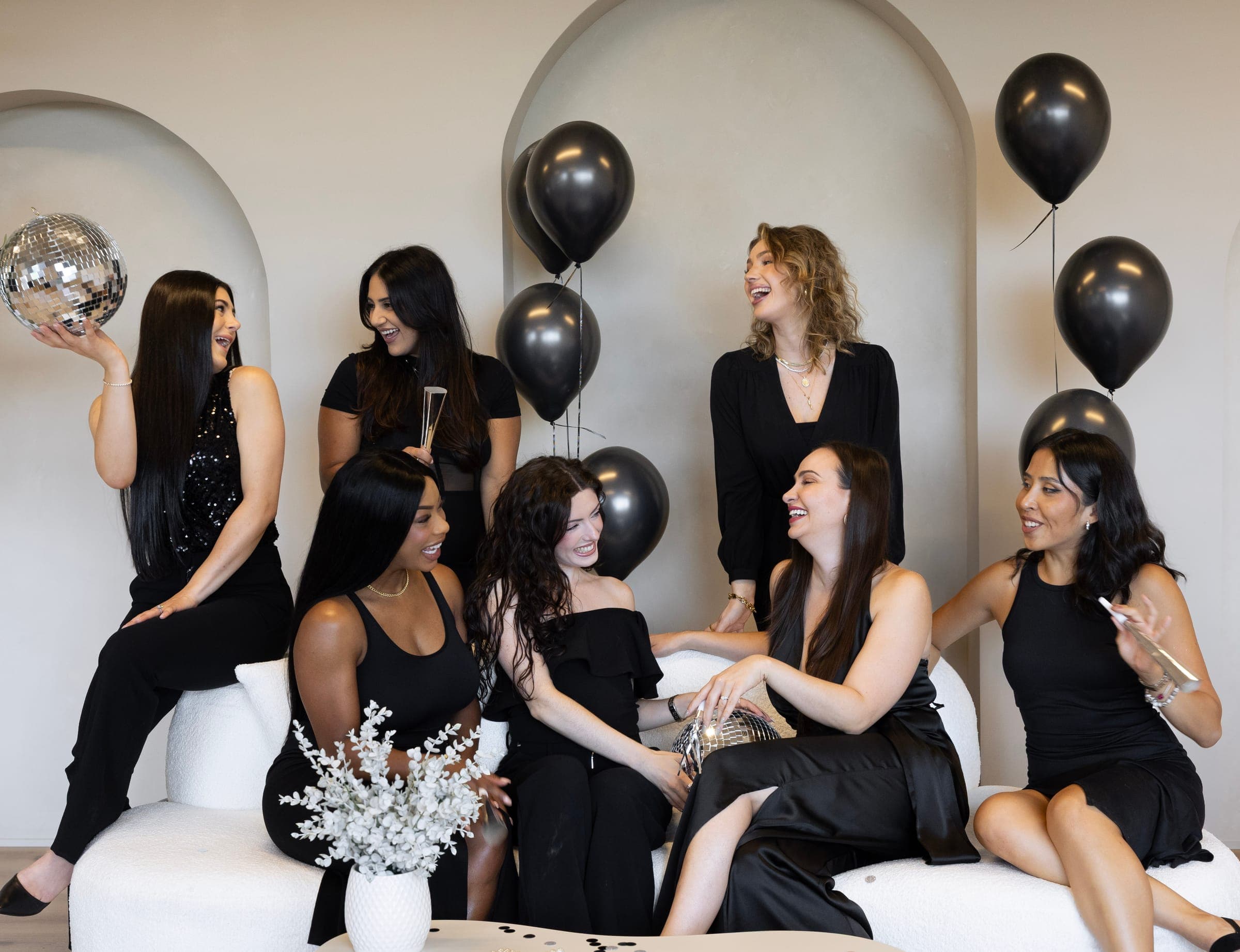 The team laughing together on a sofa with black balloons and a disco ball