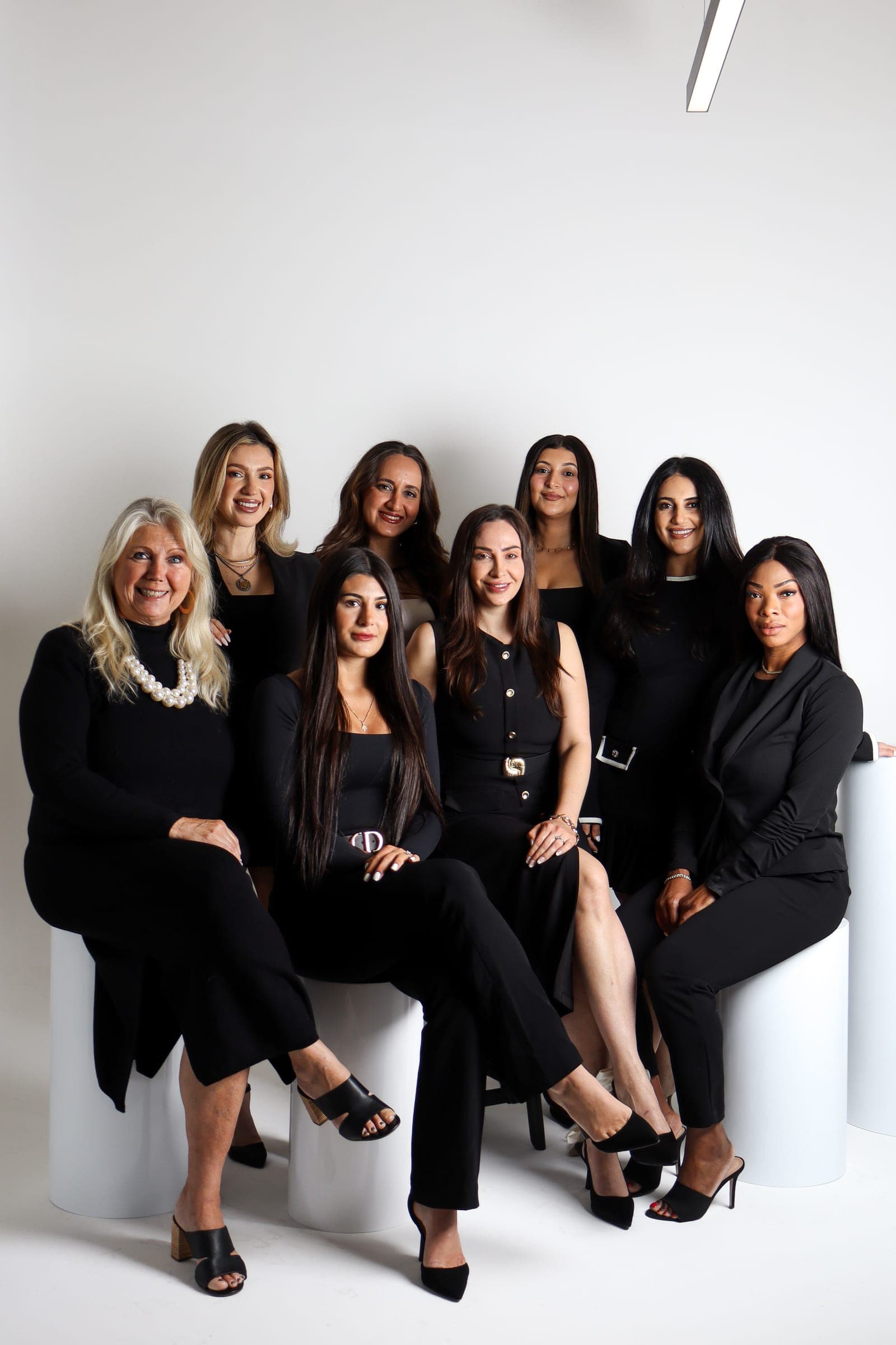 The full Reality Group team in black outfits seated together on white cylinders